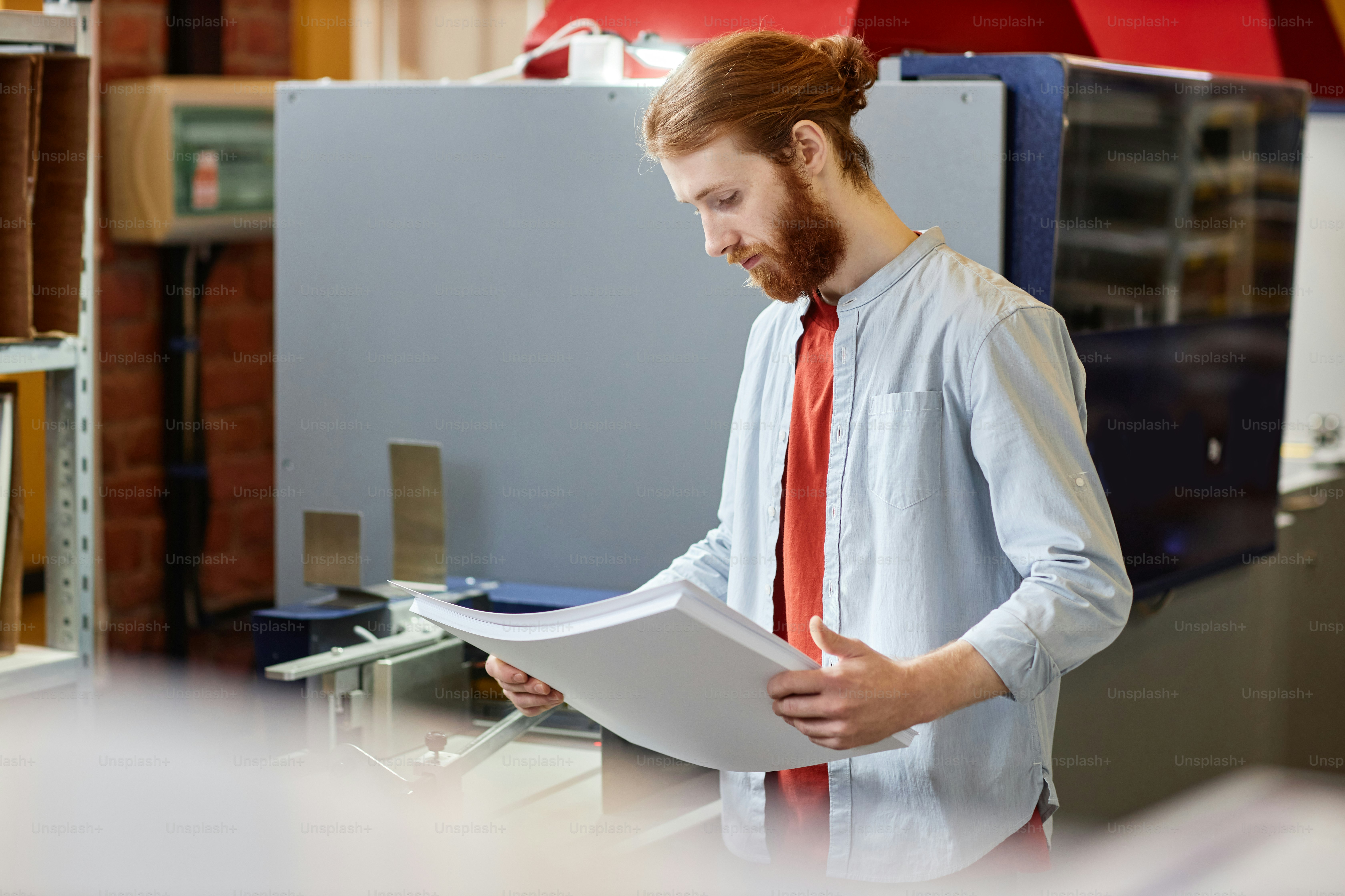 Side view portrait of smiling young man by industrial printing machine at workshop, copy space
