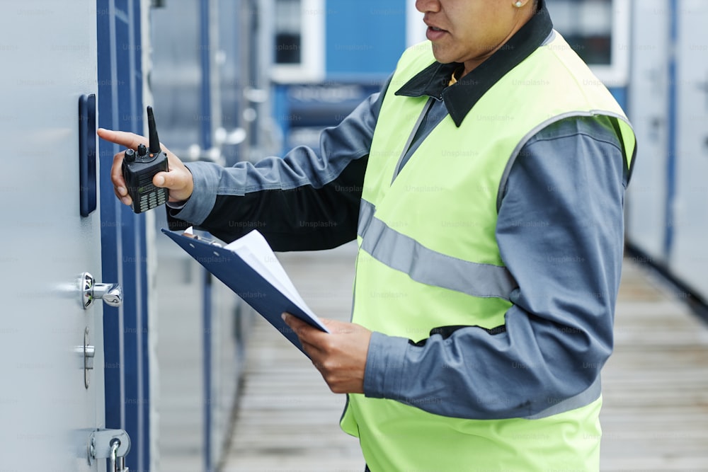Cropped shot of worker entering key code on storage unit and holding clipboard