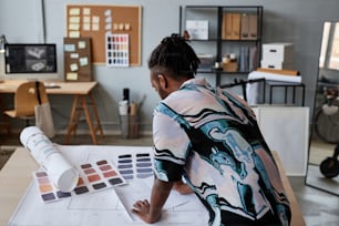 Back view portrait of male architect working on floor plans in office, copy space