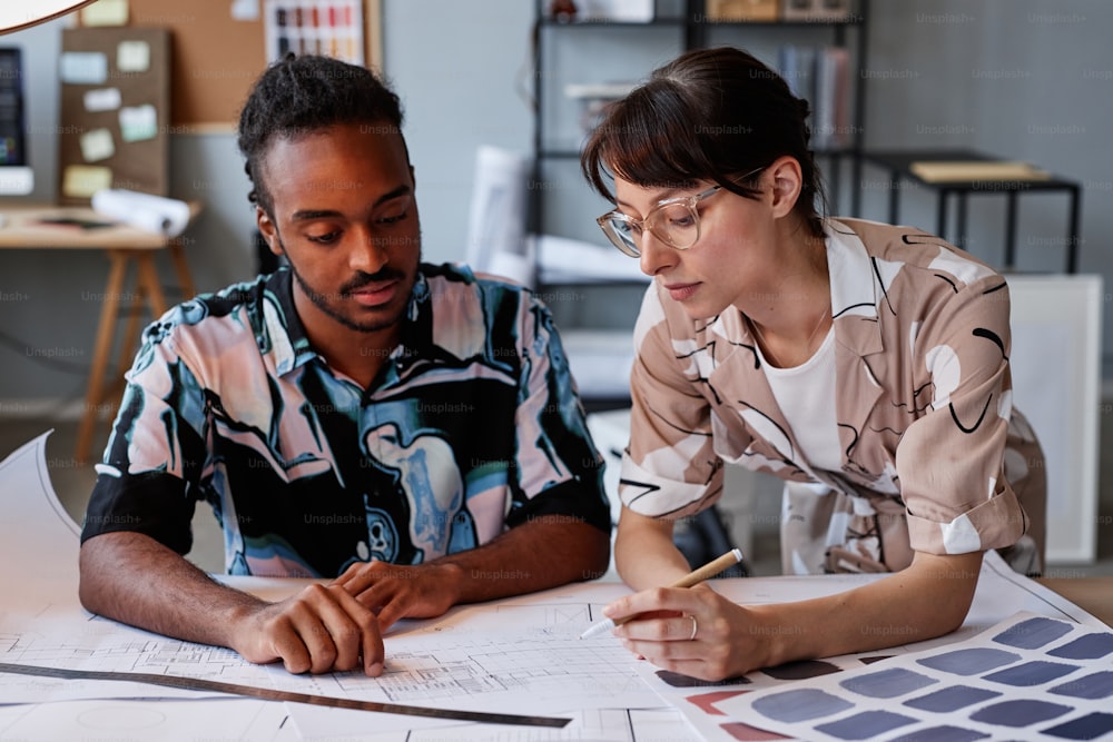 Portrait of two young architects working on floor plans for interior design project, copy space