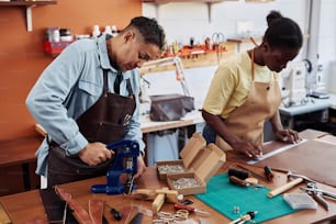 Portrait of two female artisans working together in leatherworking shop and creating handmade pieces