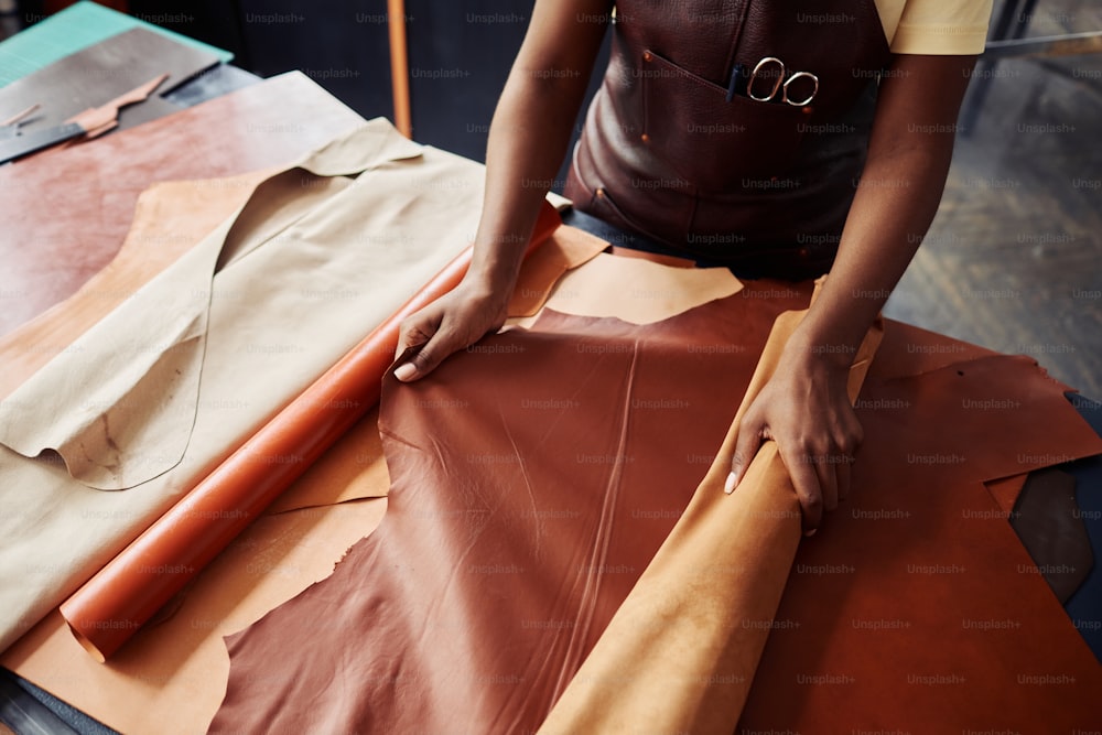 Top view close up of black female artisan working with genuine leather in workshop, copy space