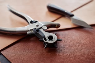 Close up of leatherworking tools on piece of genuine leather, copy space