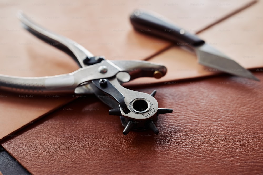 Close up of leatherworking tools on piece of genuine leather, copy space