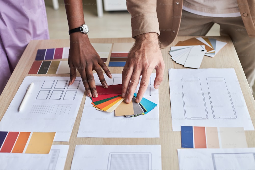 Gros plan de deux designers choisissant des échantillons de couleurs tout en travaillant sur un projet UX au bureau