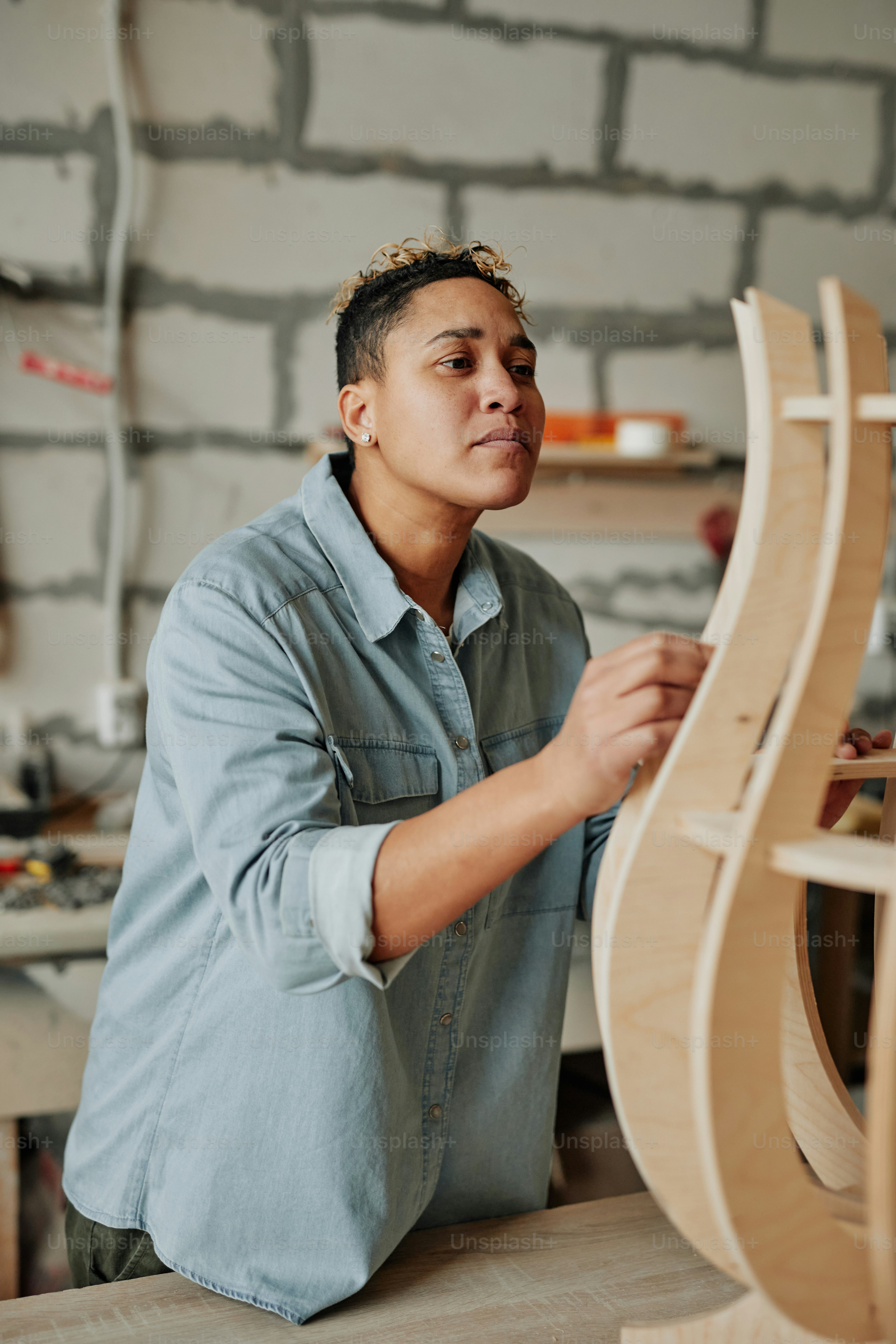 Retrato vertical do carpinteiro feminino moderno que projeta a peça de mobiliário de madeira no interior da oficina