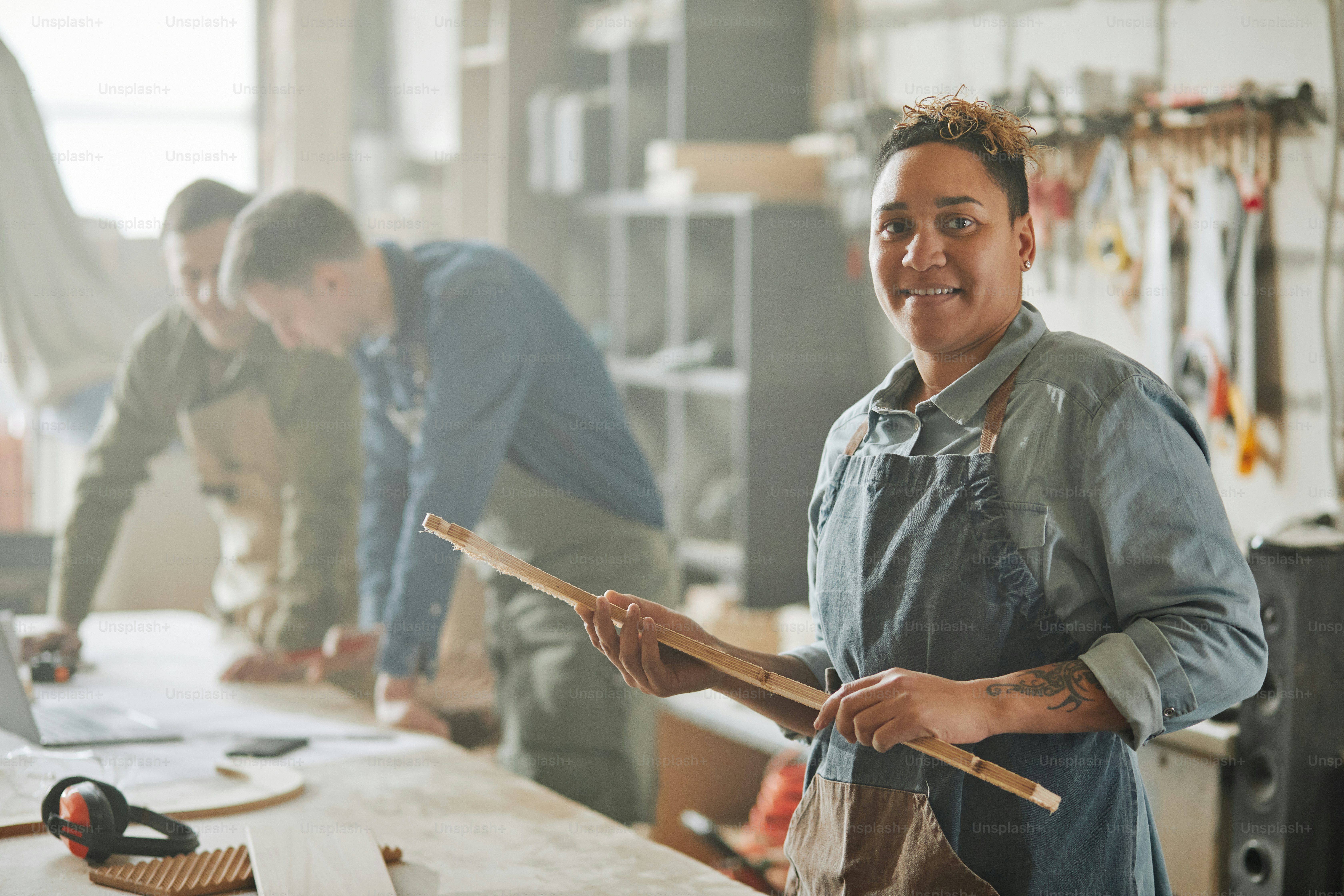 Cintura para cima retrato de artesã feminina latino-americana olhando para a câmera na oficina nebulosa, espaço de cópia