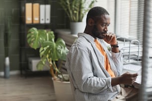 Side view portrait of smiling African American businessman working at home and reading documents with data, copy space