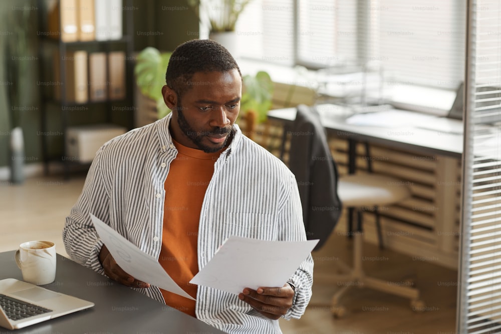 Retrato de un hombre de negocios negro adulto que trabaja en la oficina en casa y analiza documentos, copia del espacio