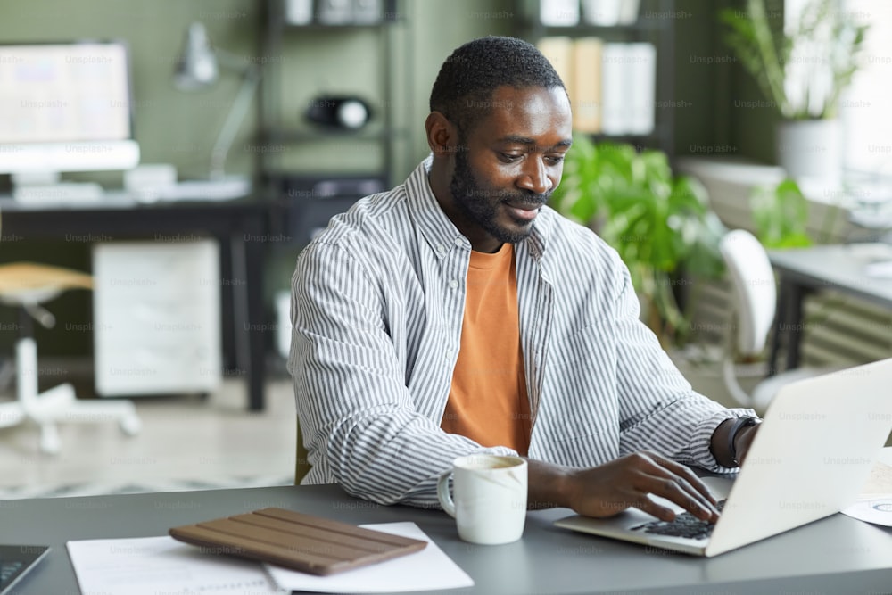 Retrato de un hombre negro adulto trabajando en la oficina en casa y usando una computadora portátil, espacio de copia
