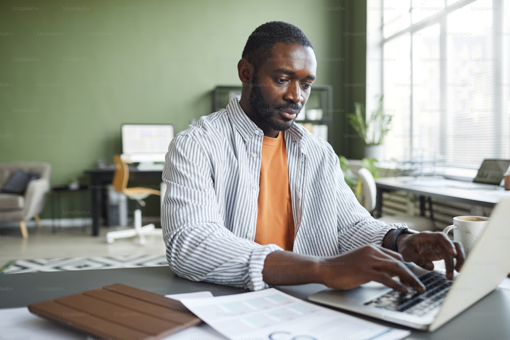 Retrato frontal de un hombre de negocios negro adulto que trabaja en la oficina en casa y usa una computadora portátil, espacio de copia