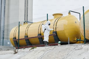 Wide angle view at worker wearing protective suit disinfecting industrial area, copy space