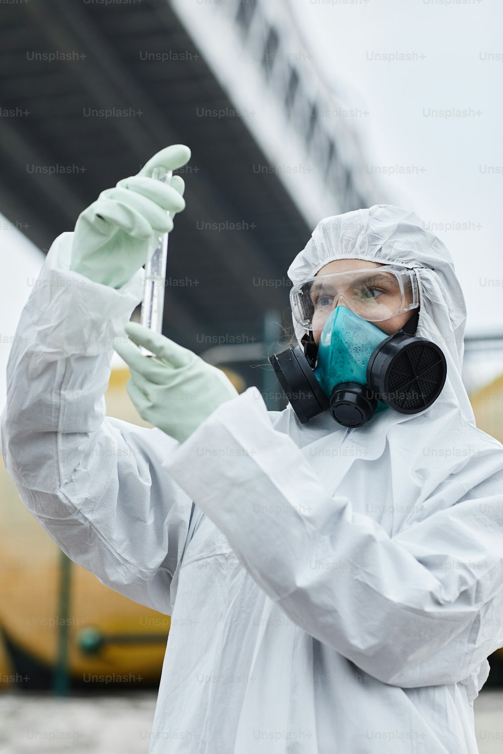 Waist up portrait of female scientist wearing hazmat suit collecting samples outdoors, toxic waste and pollution concept