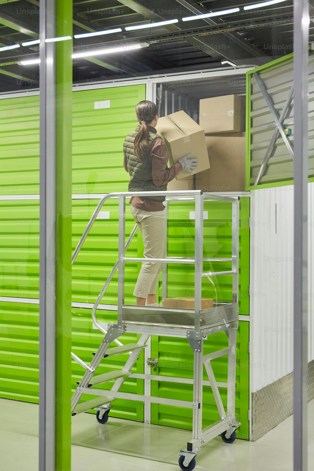 Trabajadora parada en la escalera y empacando cajas que trabaja en el servicio de entrega