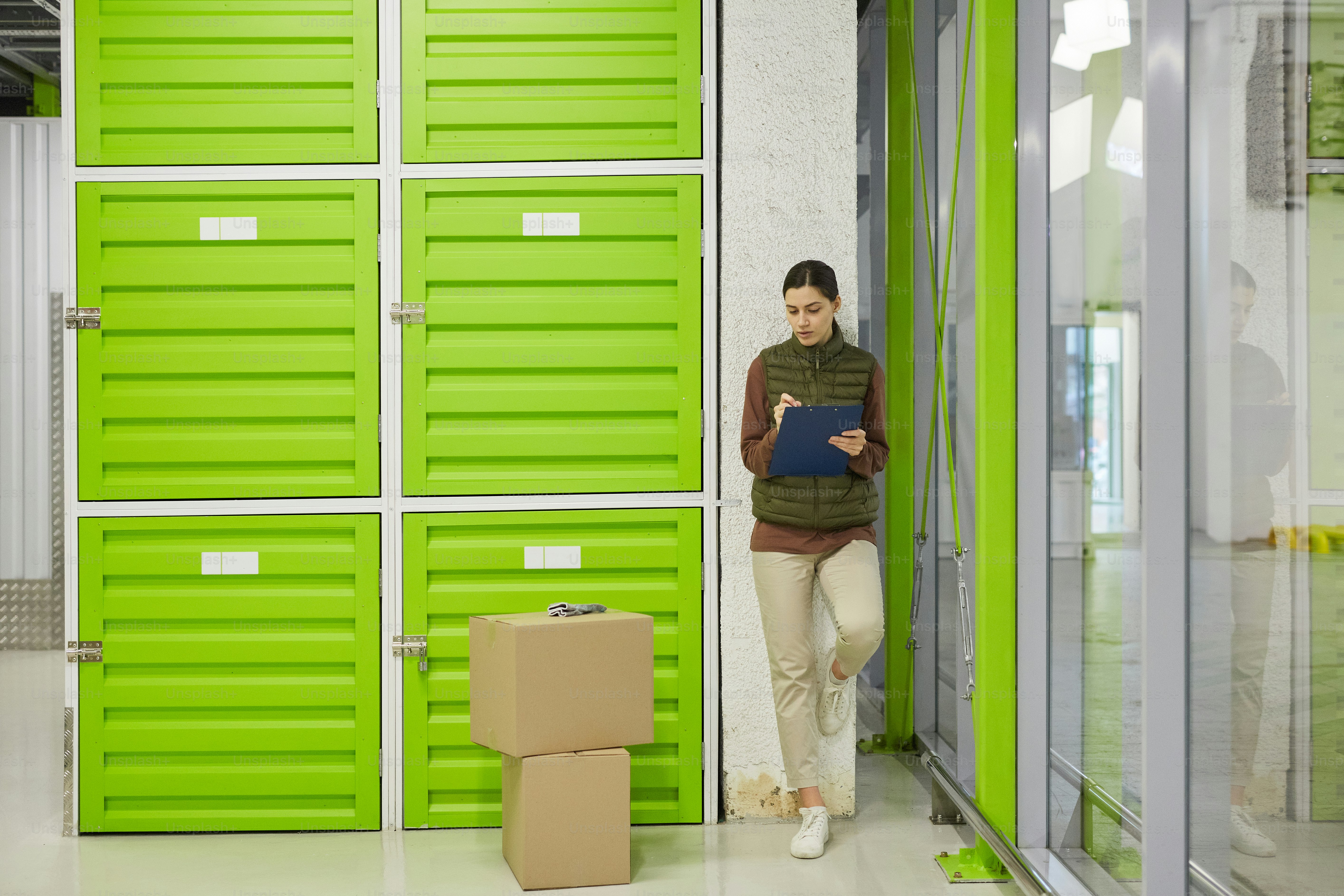 Young worker making notes in document she registrating parcels before delivery in warehouse