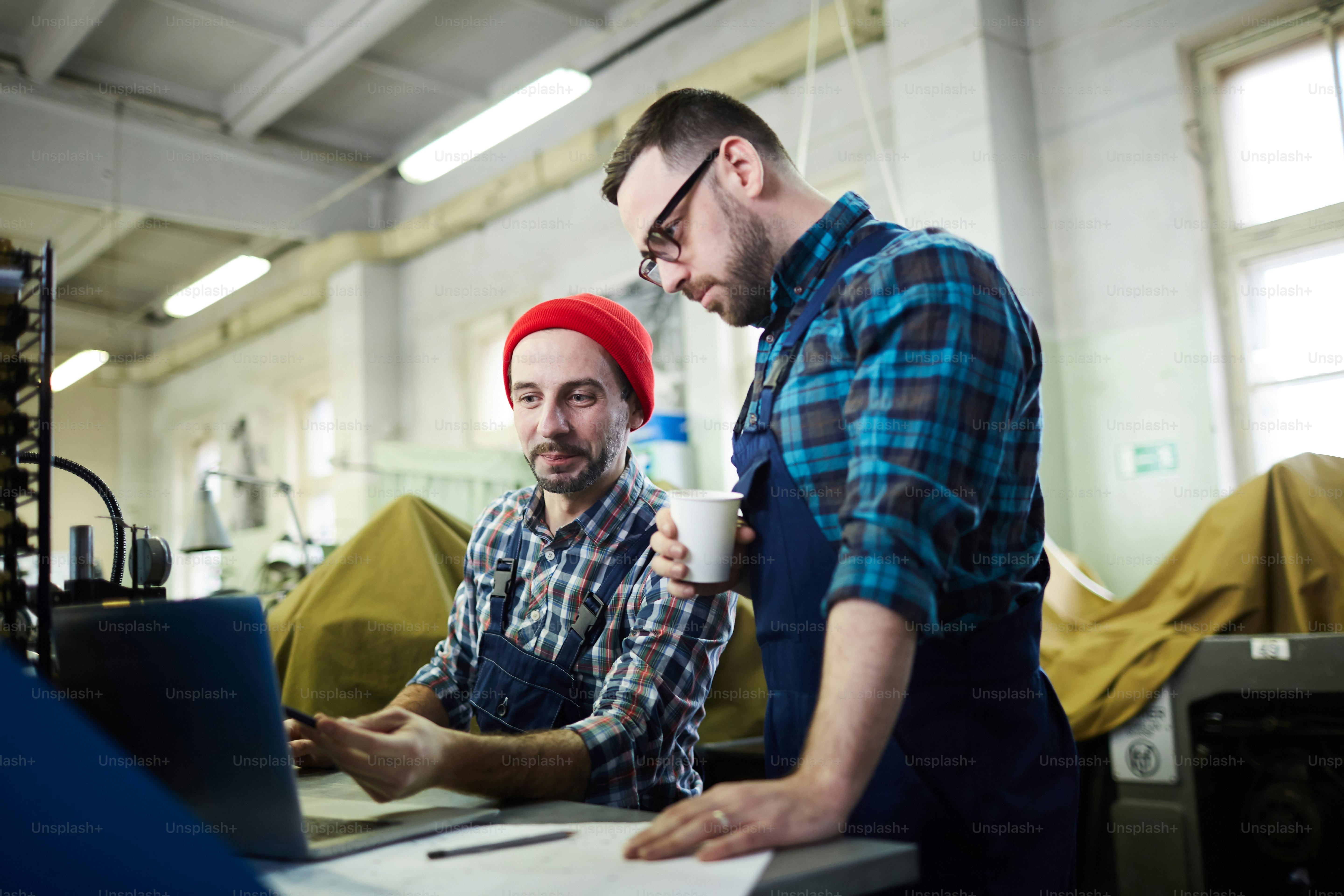 Side view portrait of mature factory workers training new employee ...
