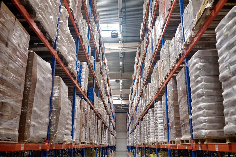 Aisle between the shelving units with cardboard boxes stacked on the pallets in the storehouse