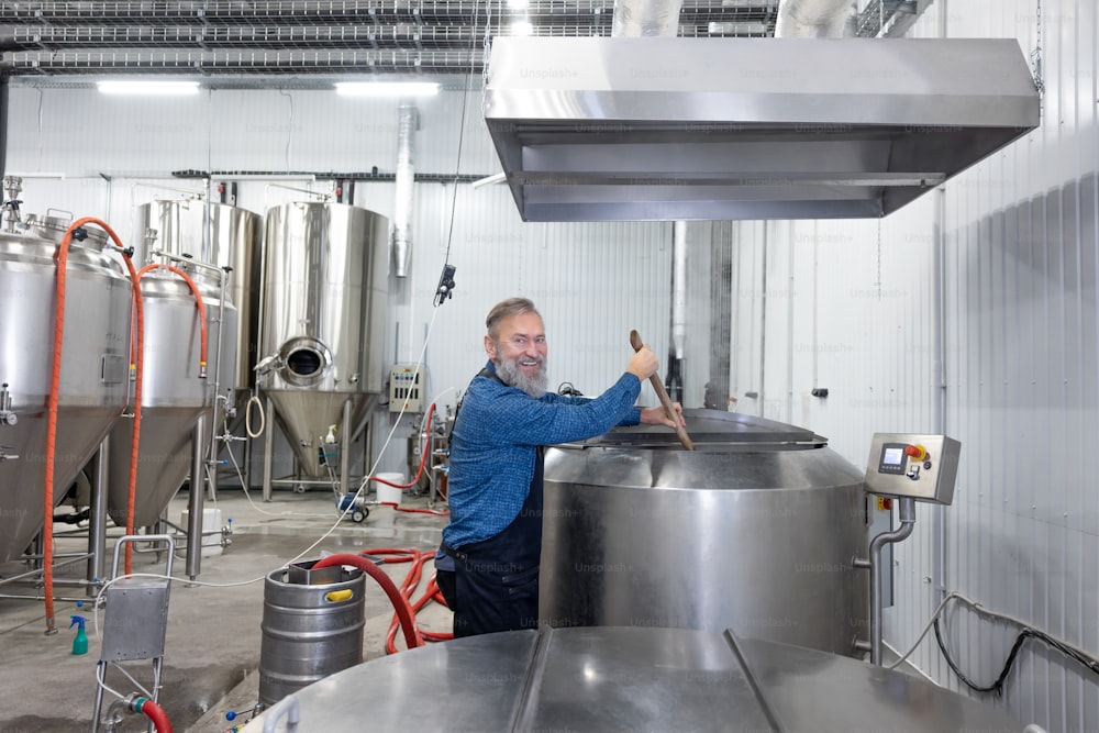 Bier umrühren. Brauereiarbeiter rührt frisches Bier in einem Tank
