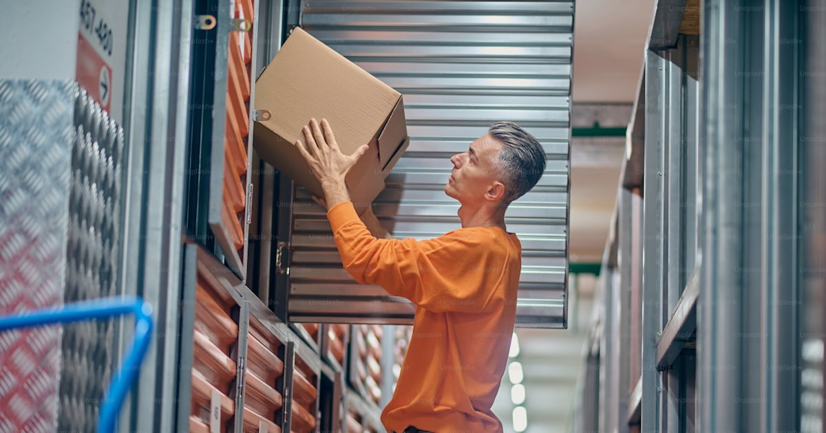 Side view of a serious focused order picker pulling an ordered item off ...