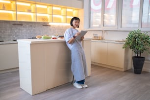 Procurando receita. Uma menina na cozinha lendo um blog de culinária on-line