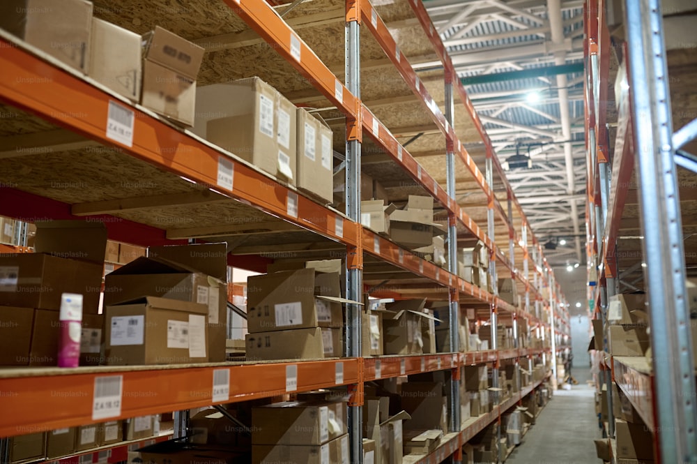 Narrow aisle in a storage area with numerous cardboard boxes arranged on the stainless steel racks