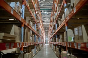Pasillo de un área de almacenamiento con numerosos estantes de acero inoxidable cargados con cajas de cartón de carga