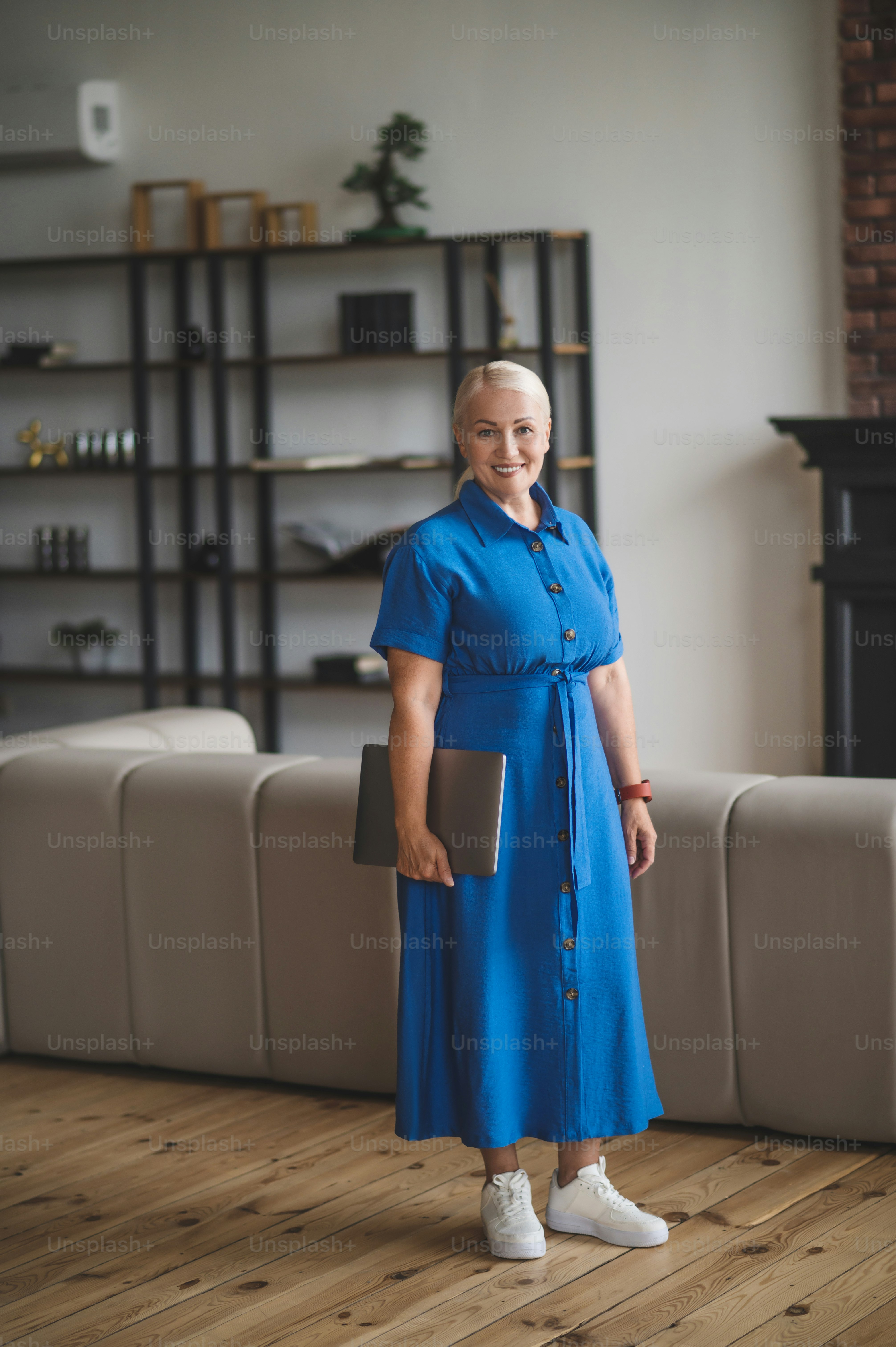 Innenministerium. Eine Frau im blauen Kleid mit einem Laptop im Zimmer