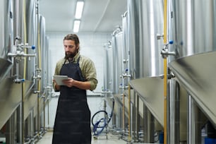 Responsable contrôlant le travail de la brasserie de bière via une application sur tablette numérique