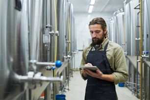 Travailleur d’une brasserie de bière artisanale avec un équipement de vérification d’ordinateur tablette