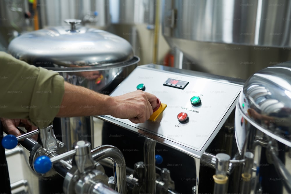 Closeup image of worker launching brewery equipment for beer fermentation and maturation