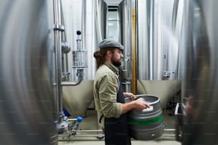 Seitenansicht eines privaten Brauereiarbeiters, der ein Fass Bier trägt