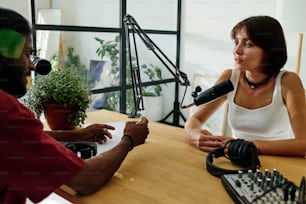 Young brunette woman listening to her guest talking about popular trends or new tendencies in business or world in studio