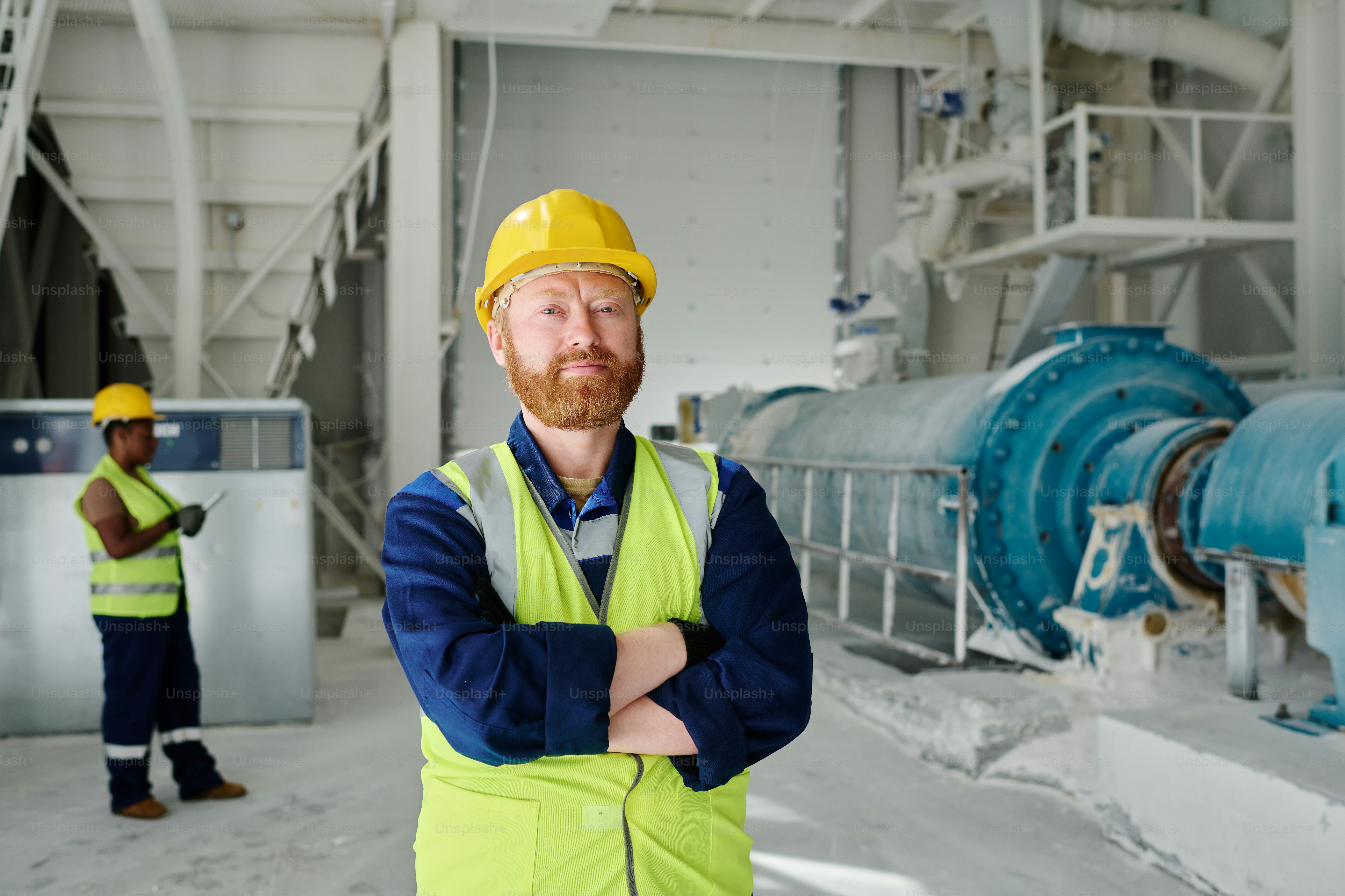 Erfolgreicher Ingenieur mittleren Alters oder Arbeiter einer Marmorfabrik in Uniform, der in die Kamera schaut, während er die Arme auf der Brust verschränkt hält