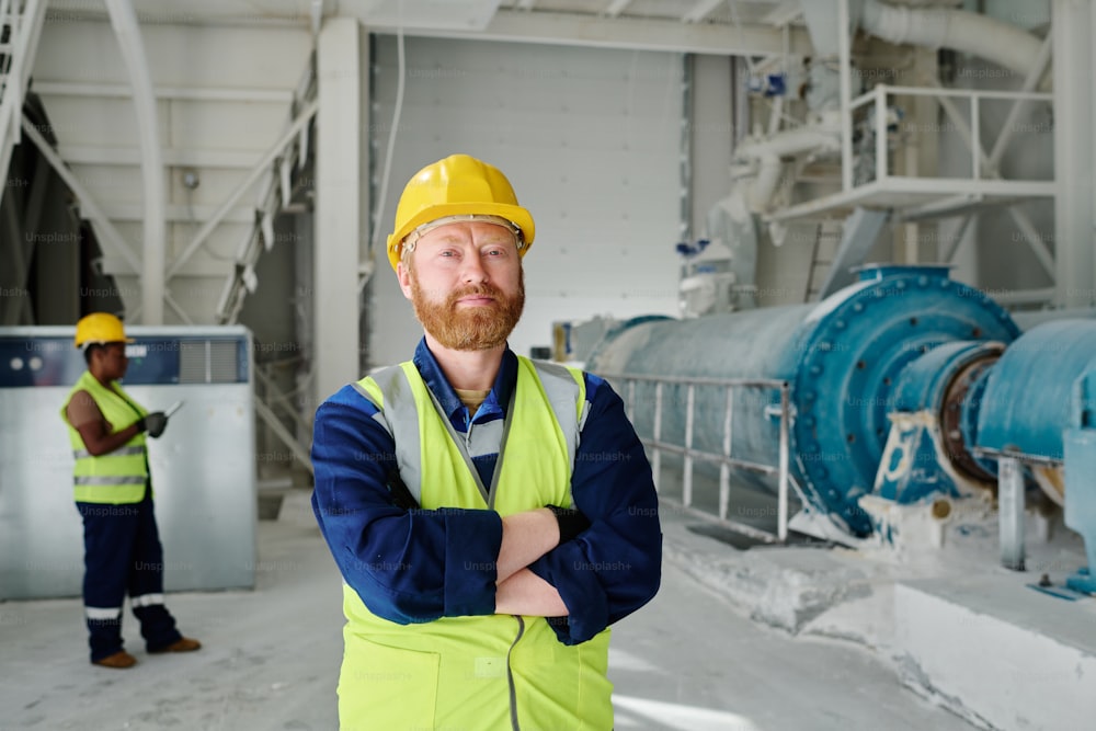 Successful middle aged engineer or worker of marble plant in uniform looking at camera while keeping his arms crossed on chest