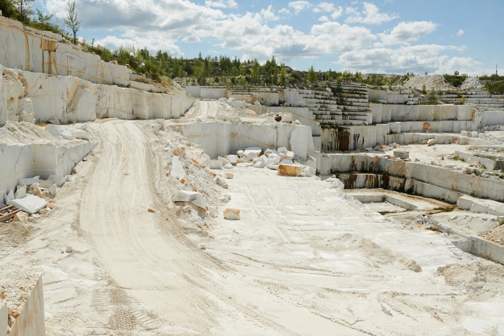Território de grande pedreira de mármore cercado por grossas paredes de pedra branca com estrada para caminhões e máquinas de construção