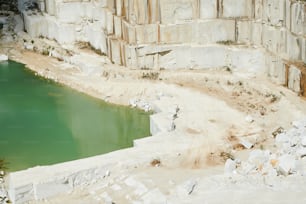大理石採石場の近代的な生産工場の囲まれた領域の一部と、巨大な白いブロックで構築された厚い壁による小さな池