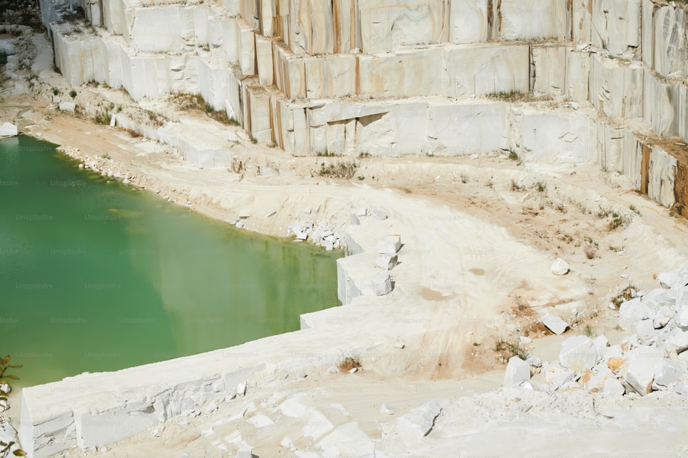 Teil des umgebenen Territoriums der modernen Produktionsfabrik im Marmorsteinbruch mit kleinem Teich durch dicke Mauer, die aus riesigen weißen Blöcken aufgebaut ist