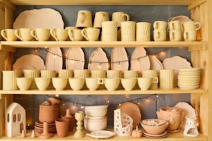 Großes Display bestehend aus drei Regalen mit handgefertigten Tonprodukten wie Bechern, Tassen, Tellern, Schalen, Töpfen und Vasen im Shop