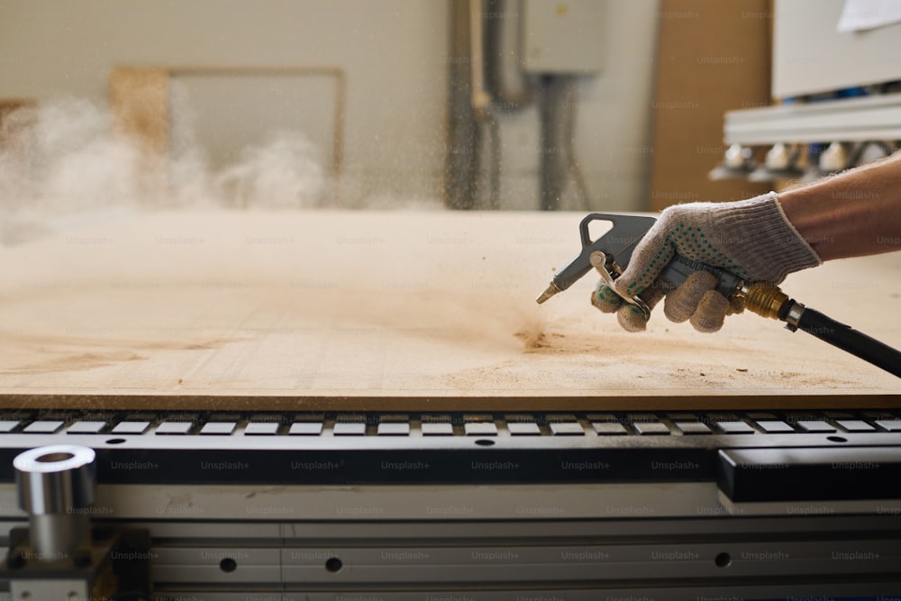 Primo piano del lavoratore in guanti che lavorano tavole di legno con attrezzature speciali alla macchina