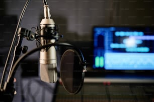 Toma horizontal de enfoque selectivo sin personas del micrófono con filtro de pop de disco y consola de mezclas en un estudio de grabación moderno