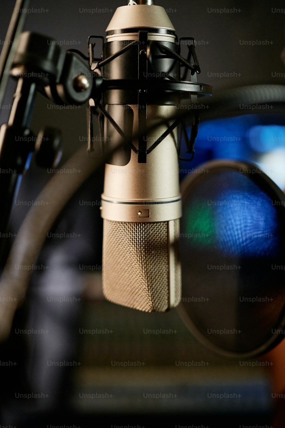 Vertical no people close-up shot of microphone with disc pop filter in modern recording studio