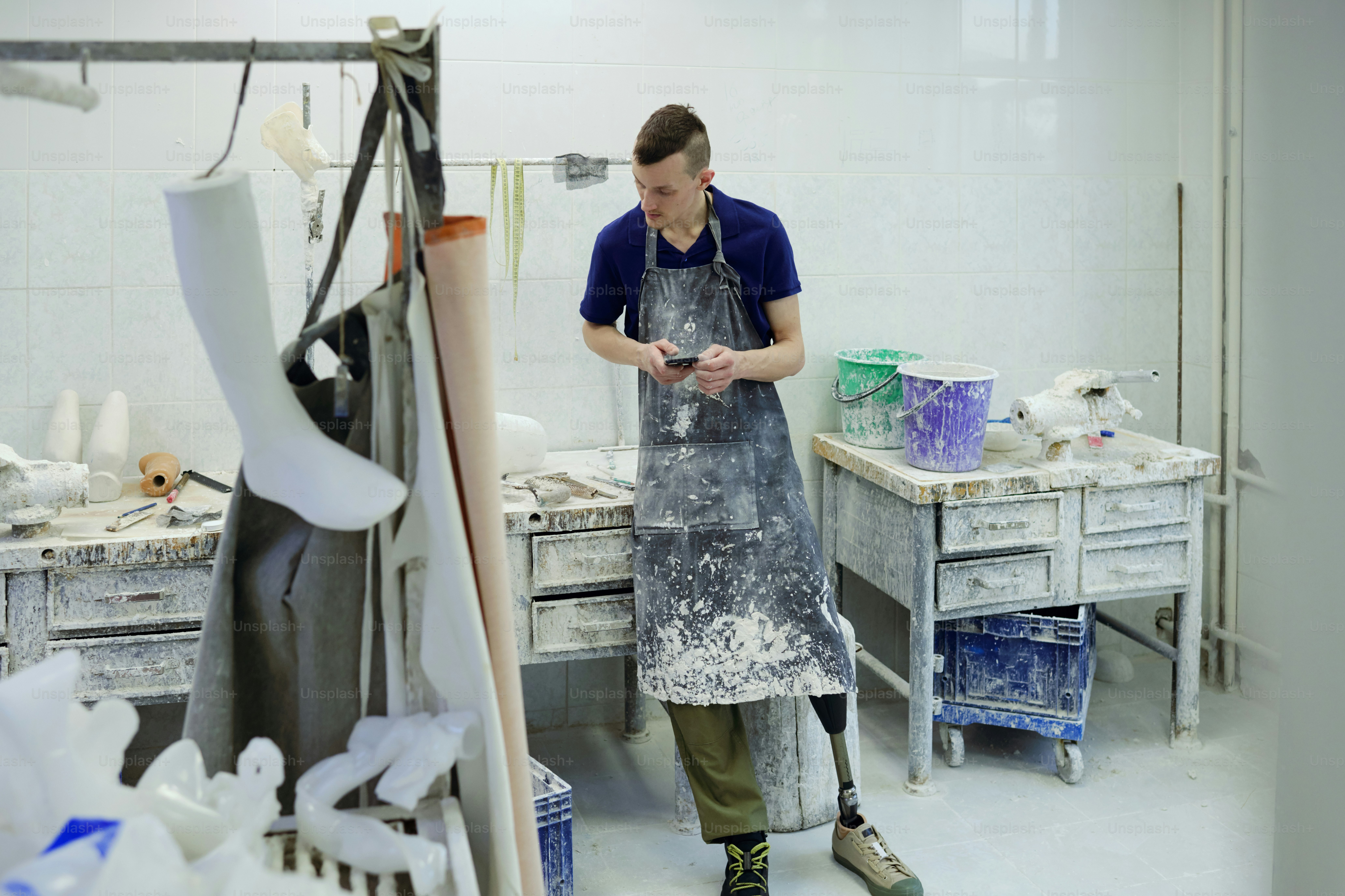 Young man in apron making revision of work supplies in prosthetic ...