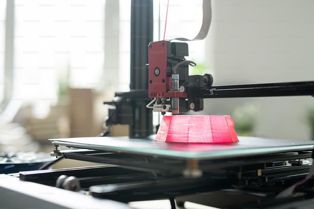 Printhead of 3d printer moving over foundation of pink round object on working layer during process of printing