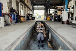 A mechanic's workshop worker sweeping dust in mechanic's pit.