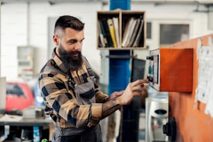 An industry worker pressing control button on machine.