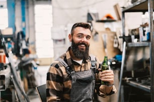 An industry worker toasts with bottle of beer and smiling at the camera.
