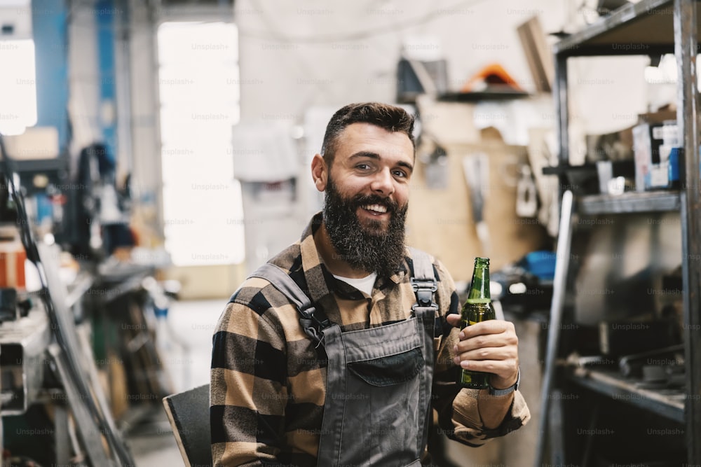 業界の労働者が�ビール瓶で乾杯し、カメラに微笑む。