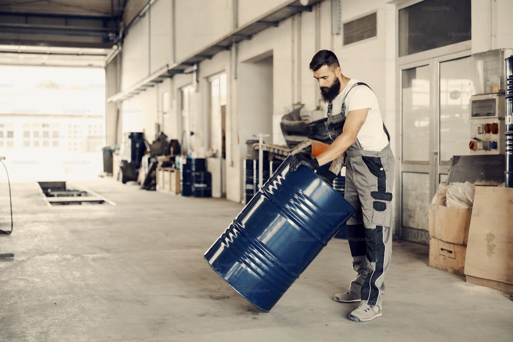 An industry worker rolling barrel with petroleum in facility.