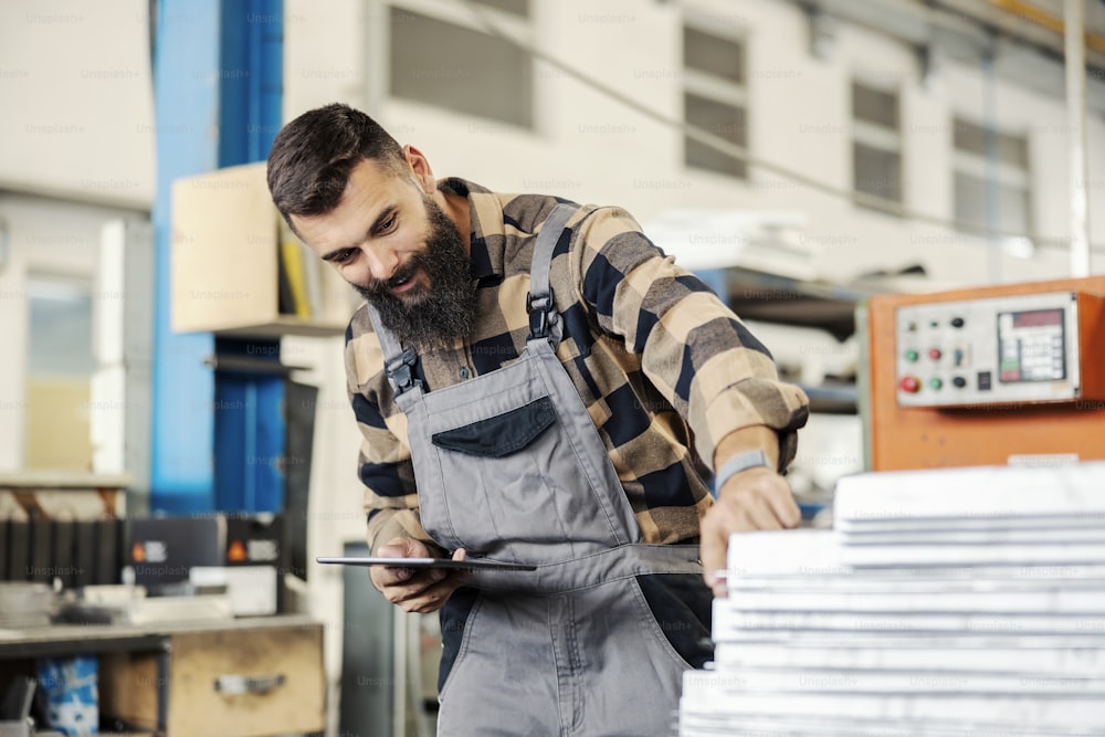 An industry worker using tablet for checking on inventory in facility.