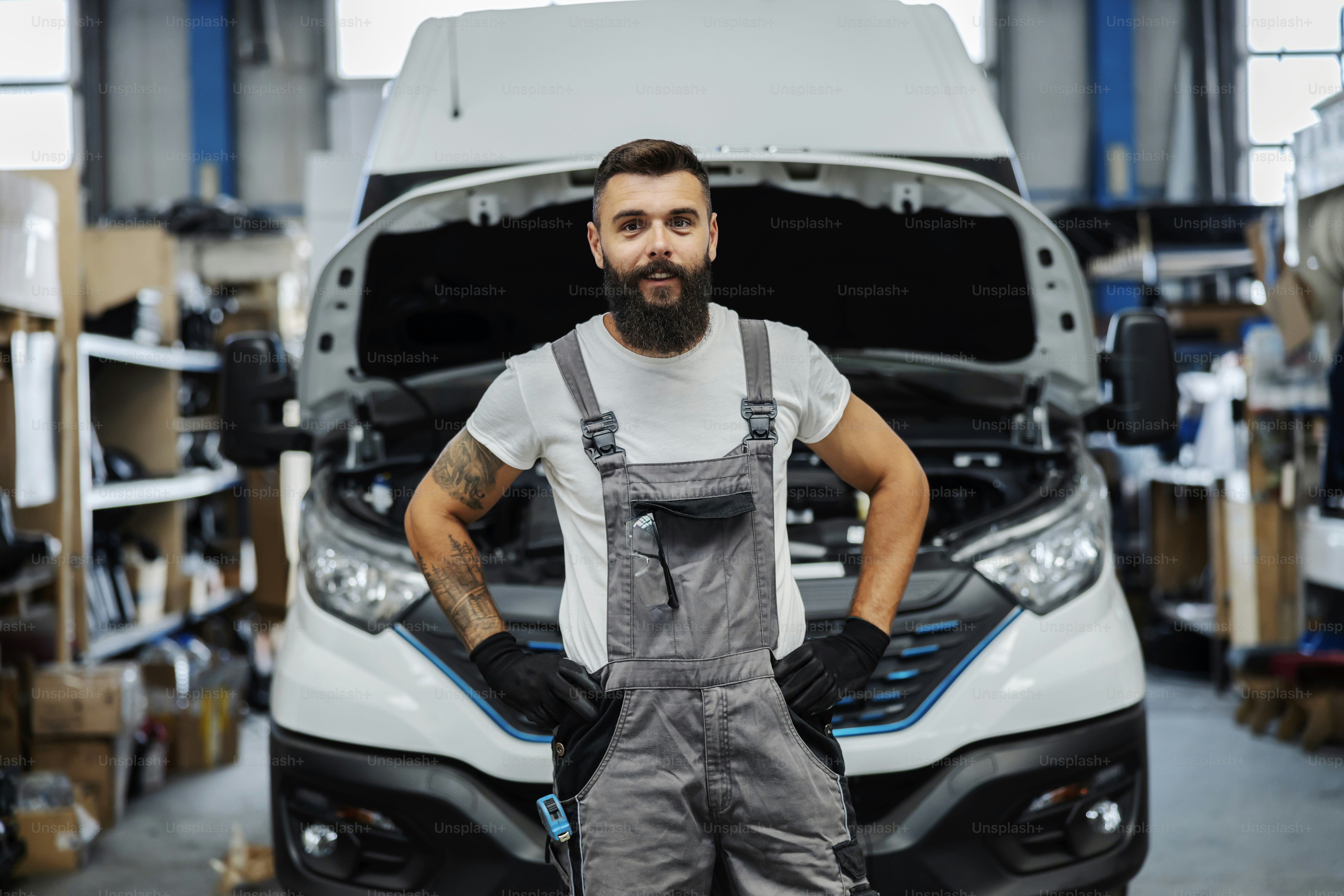 A smiling auto-mechanic at workshop looking at the camera.
